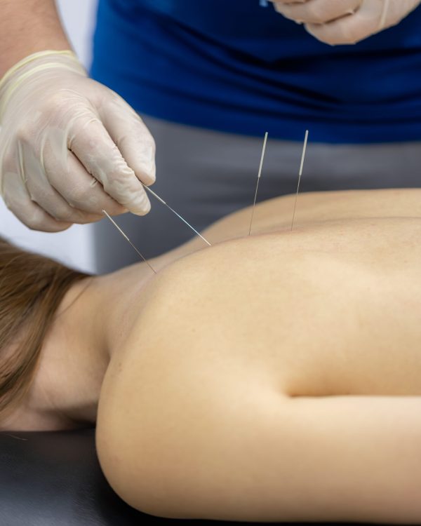 During consultation a gloved doctor examines the shoulder and collarbone area while the female patient focuses on sensations. Neutral clinic interior suits medical content about painrelief and recovery.