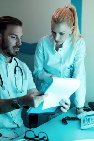 Two doctors cooperating while reading patient's medical documents in the hospital.
